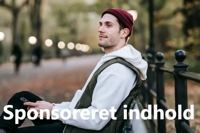 Mand sidder på bænk og spiller på mobil